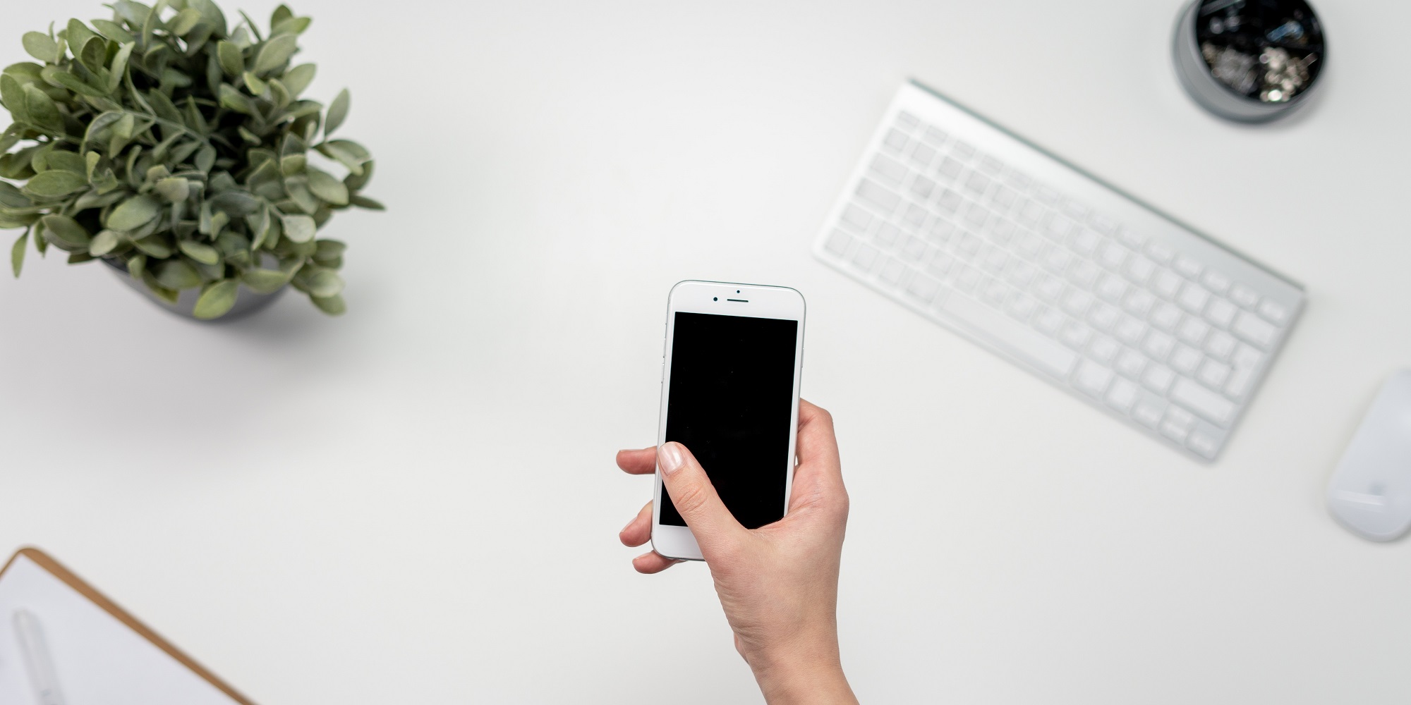 Someone holding a mobile phone over a desk